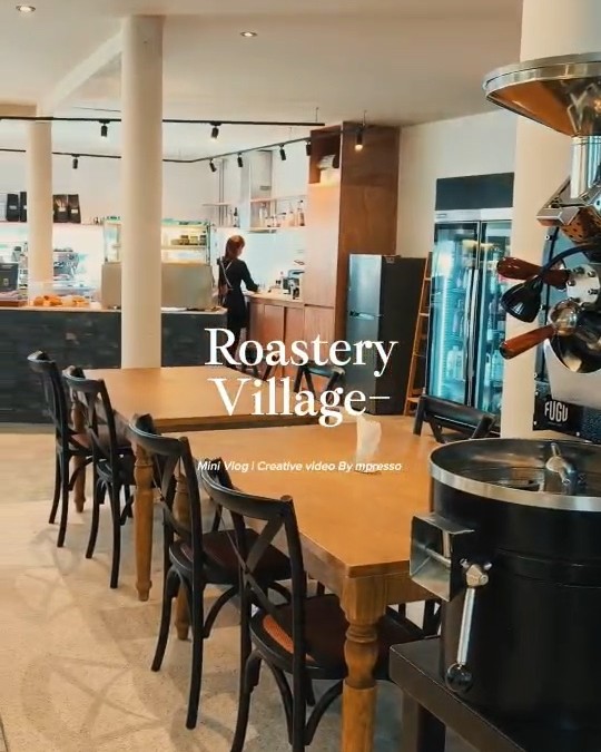The room at Roastery Village in Bophut — long wooden tables, chairs and the roaster in the corner